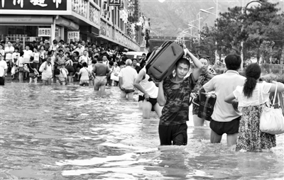 昨日，一名消防戰(zhàn)士在秦皇島市山海關(guān)火車站站前廣場涉水幫助旅客運送行李。 新華社發(fā)